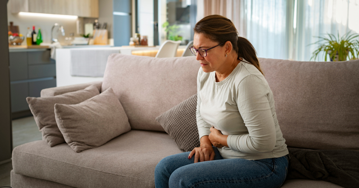 Woman with abdominal pain sitting on couch