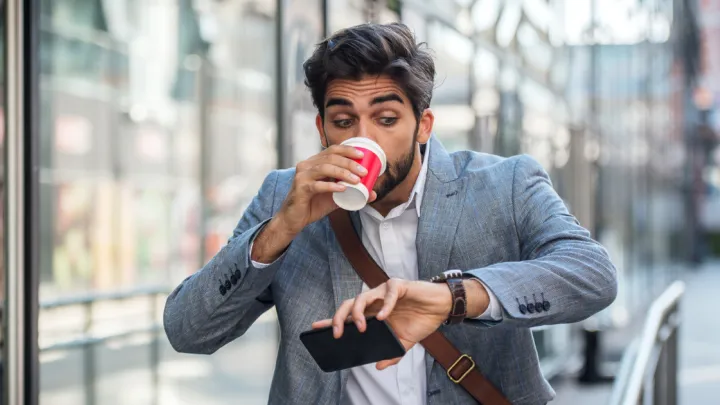 Man drinking coffee and looking at his watch
