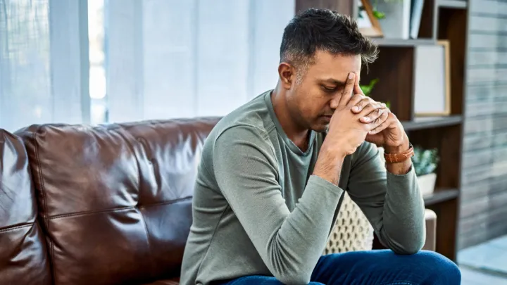 Man sitting on couch with head in hands