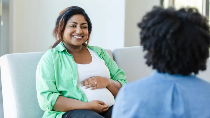 Pregnant woman sitting, talking to doctor