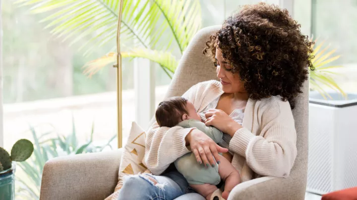 Woman sitting in a rocking chair breastfeeding her baby