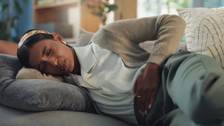 Woman lying on couch holding stomach