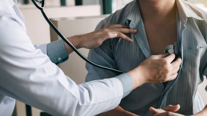 Doctor listening to man's heart