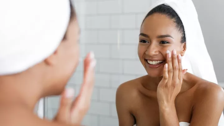 Woman applying cream to her face